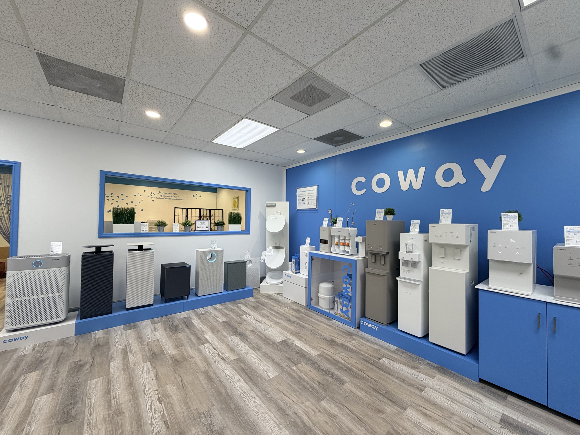 Inside the Coway Houston showroom — the blue Coway wall with the water purifier and air purifier lineup on display